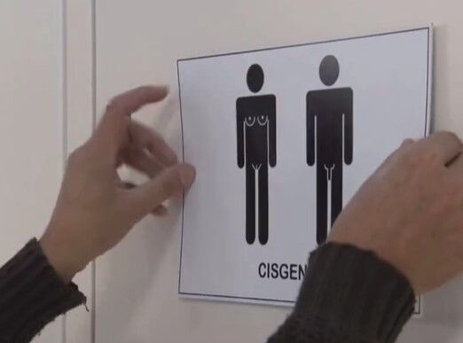 Two hands taping a "cisgender" sign to the wall