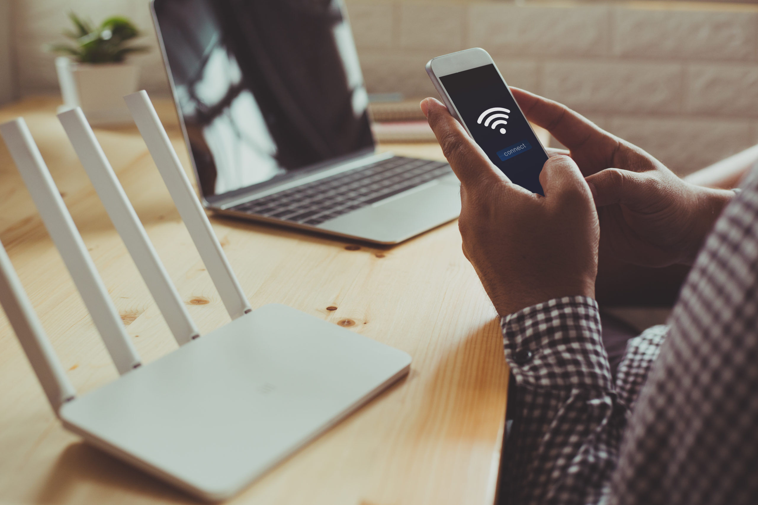 closeup of a wifi router and a man using smartphone on living room