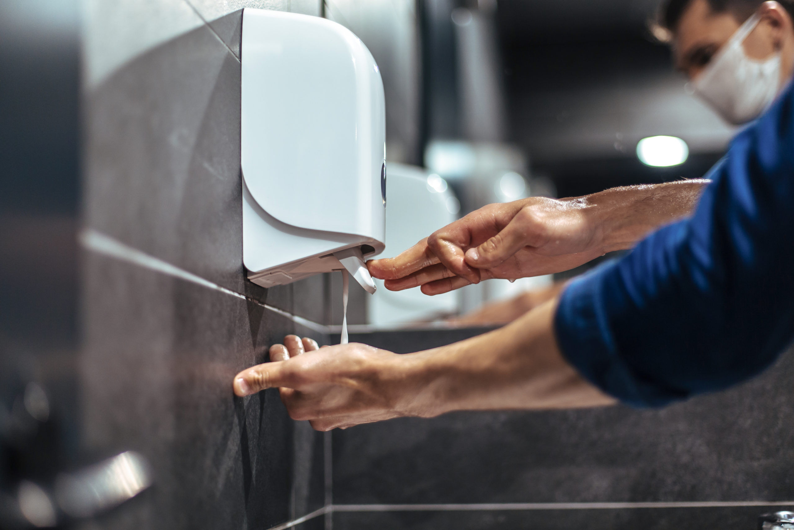 men carefully washes their hands in a restroom