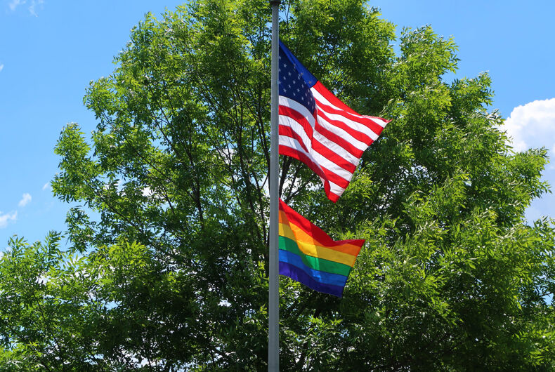 One flag pole flying an American flag and a rainbow flag.