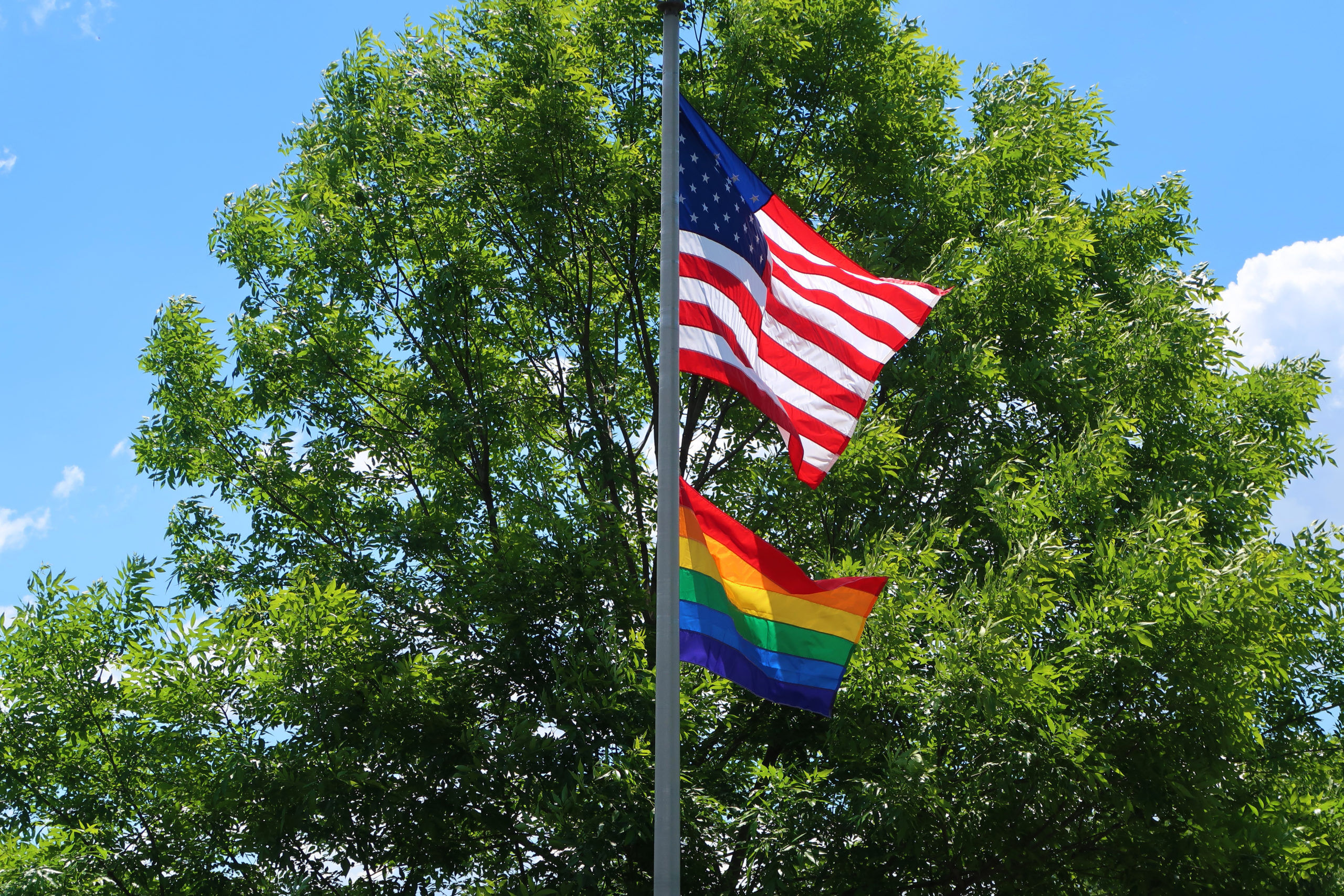 One flag pole flying an American flag and a rainbow flag.