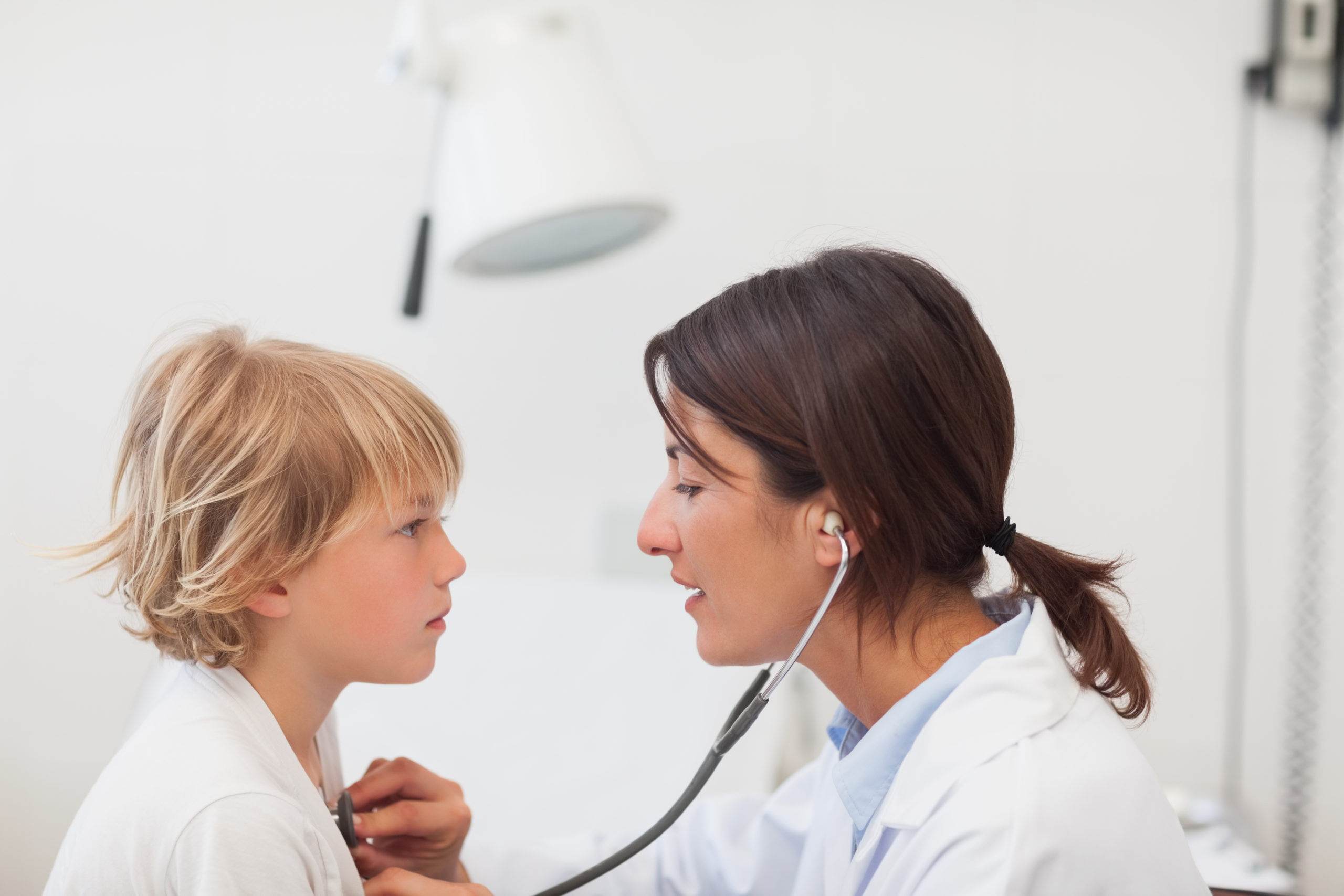 Doctor auscultating a child/youth with a stethoscope in examination room, Healthcare workers in the Coronavirus Covid19 pandemic