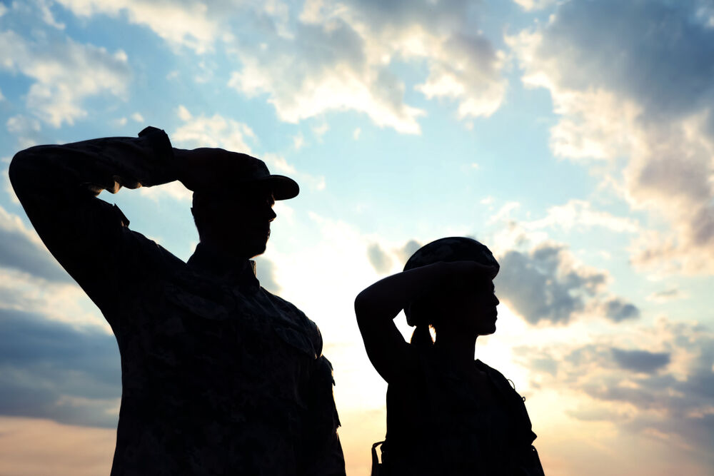Two silhouettes of people in the military saluting