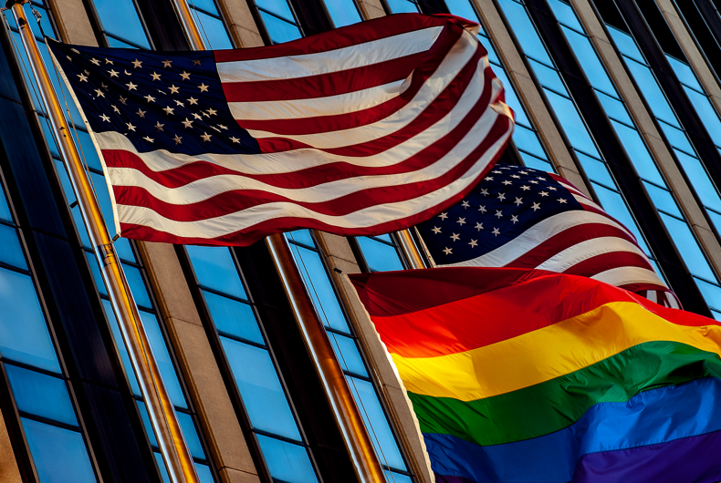 Two American flags waving just above a Pride flag