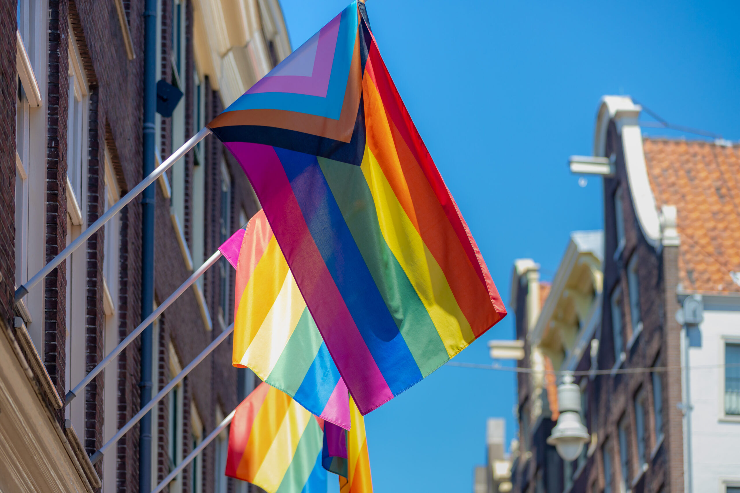 Progress pride flag (new design of rainbow flag) waving in the air with blue sky, LGBTQ community in Netherlands