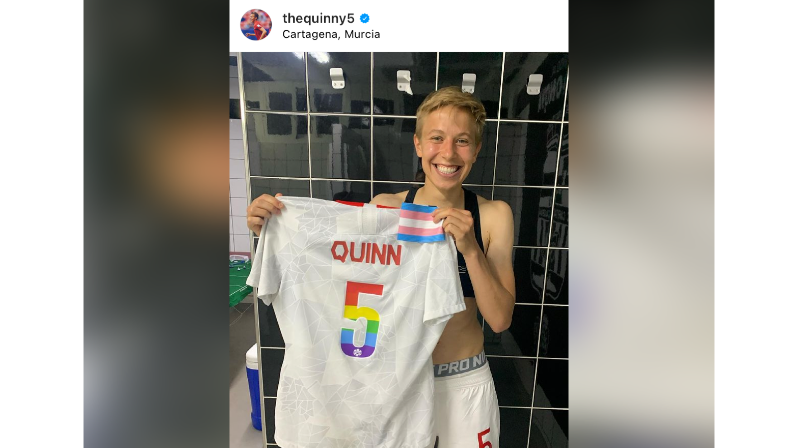 Soccer player Quinn holding up their Pride-colored jersey as well as a small trans flag.
