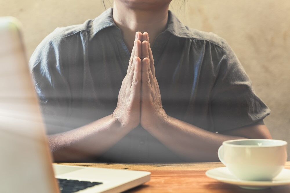 A computer worker praying. Also coffee. It's a stock image, not Lorie Smith.