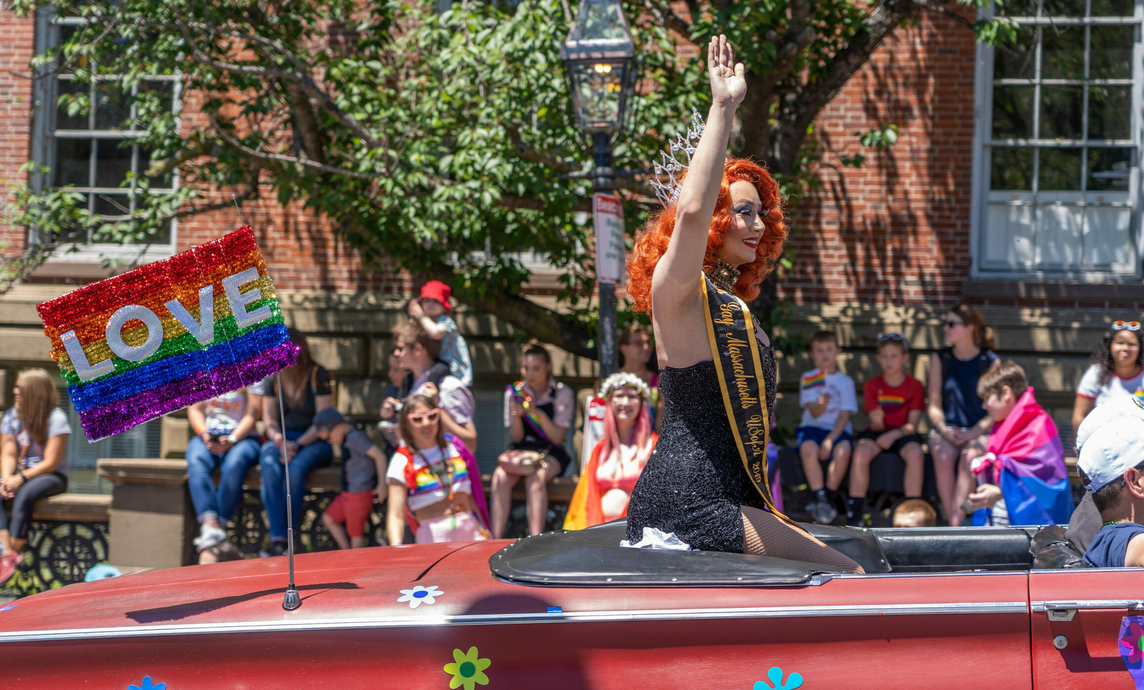 Boston, US - June 8,2019: Miss gay Massachusetts sitting in red car with rainbow flag of LOVE