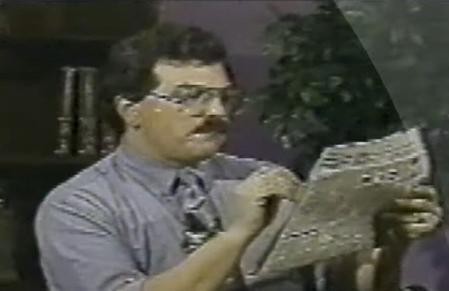 Bob Enyart reading a newspaper during a Jan 9, 1995 broadcast.