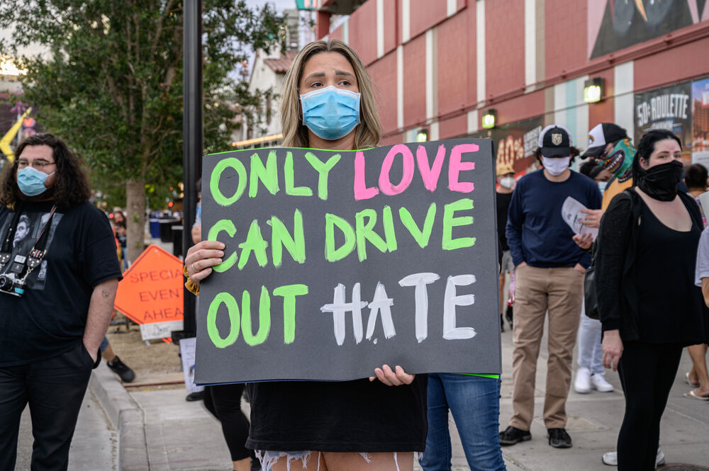 Protestor holding sign that says "Only love can drive out hate."