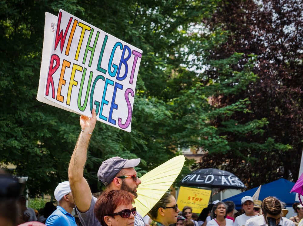 June 30 2018 - A man in Detroit holds a protest sign above the crowd that says "With LGBT Refugees."