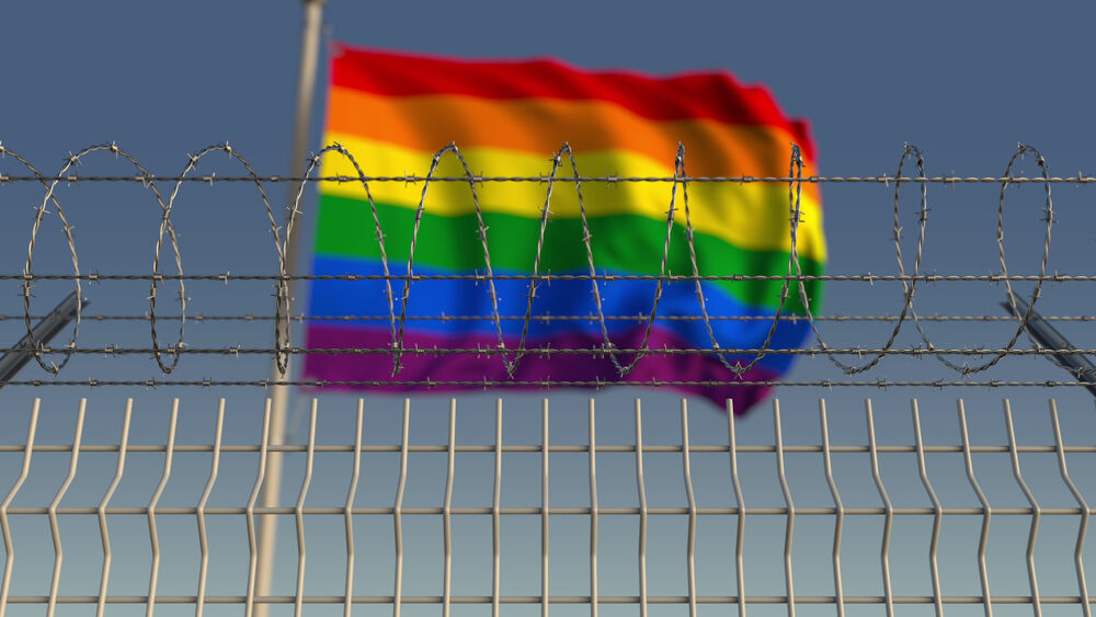 A rainbow flag behind barbed wire