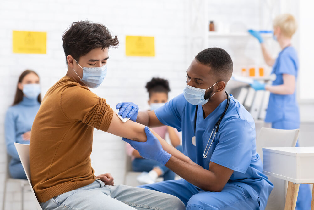 A medical worker with a mask giving a man with a mask a shot