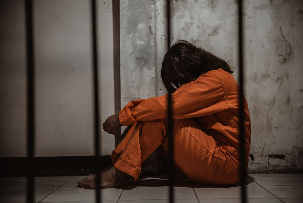 a sad woman in prison wiht her head between her knees
