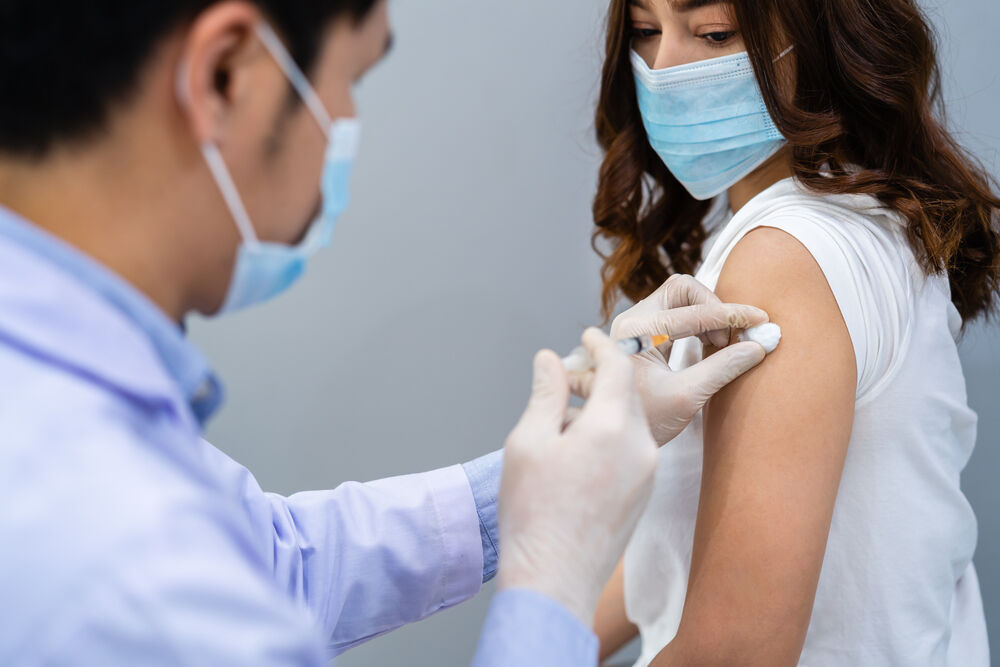 doctor injecting the vaccine into someone with a mask