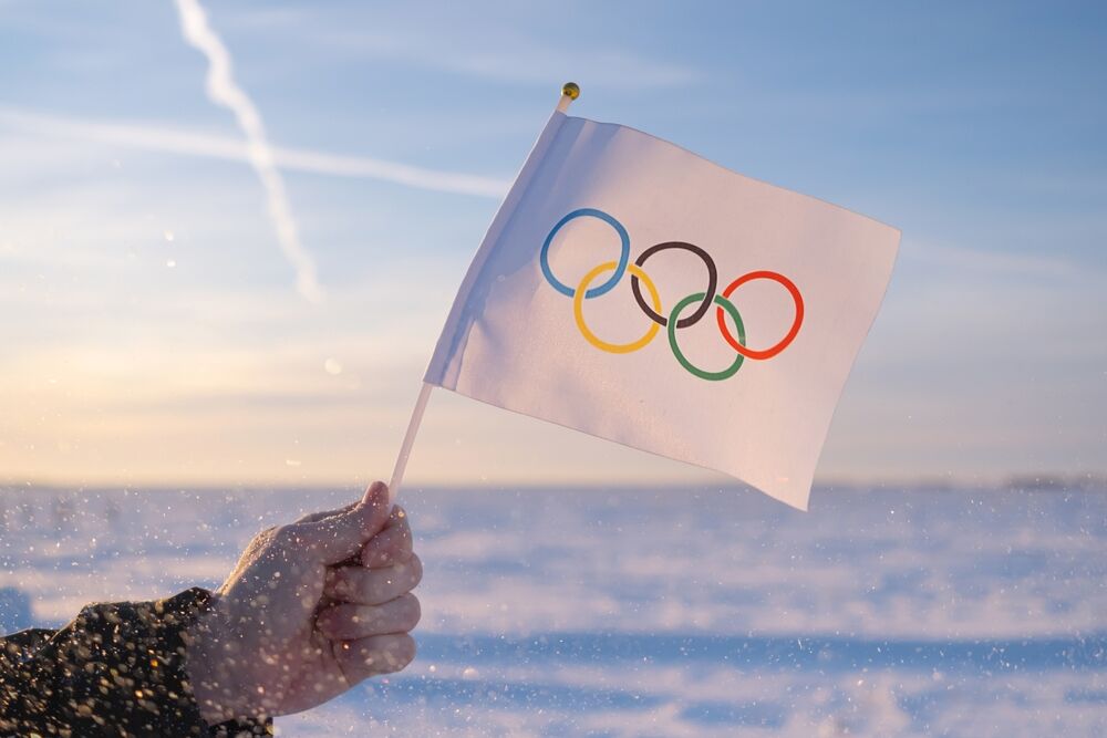 Winter Olympics flag with snow in the background