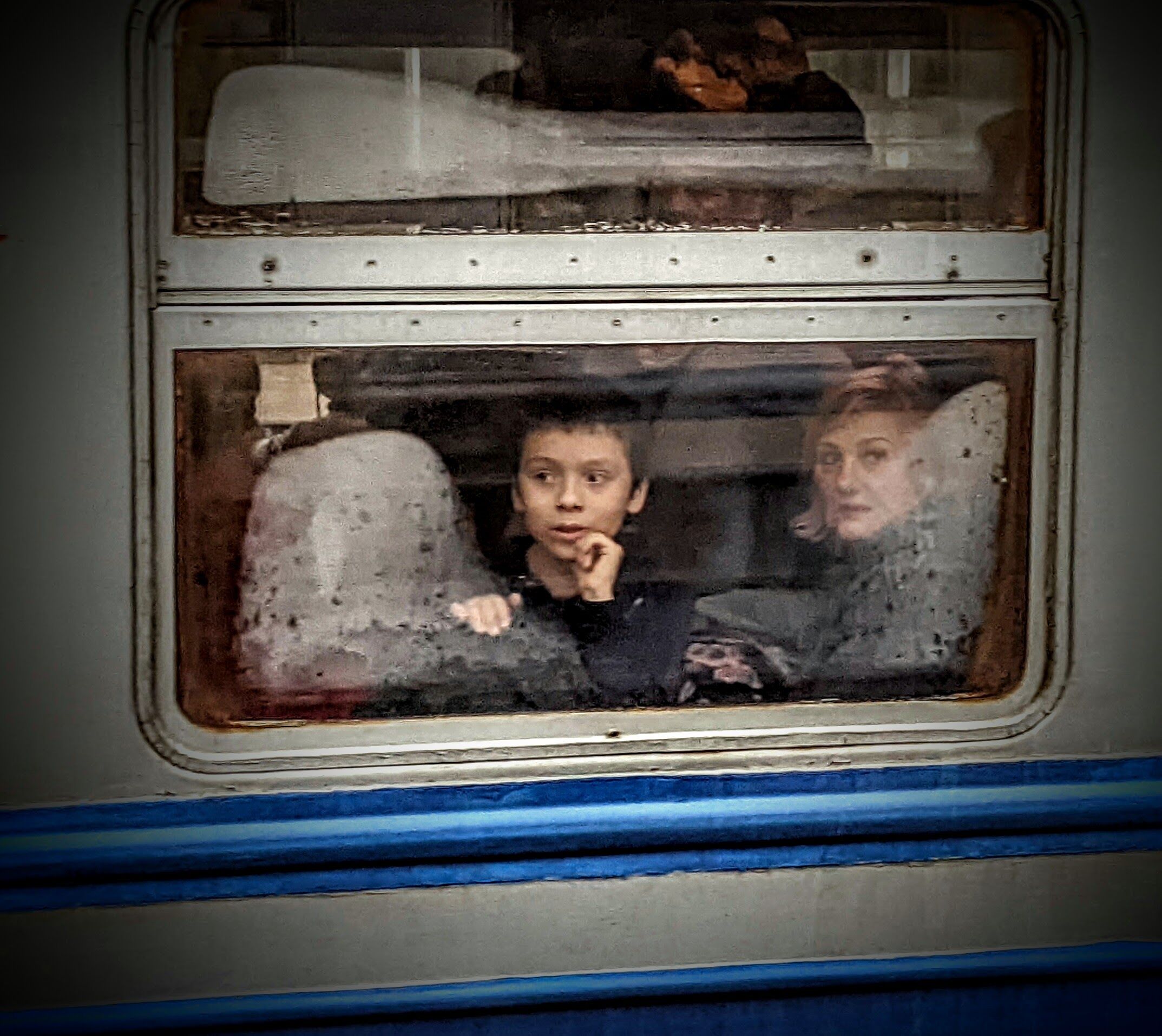 3/5/22: A boy looks out the window on a train that is being held at the Ukrainian - Polish for entry into Poland.