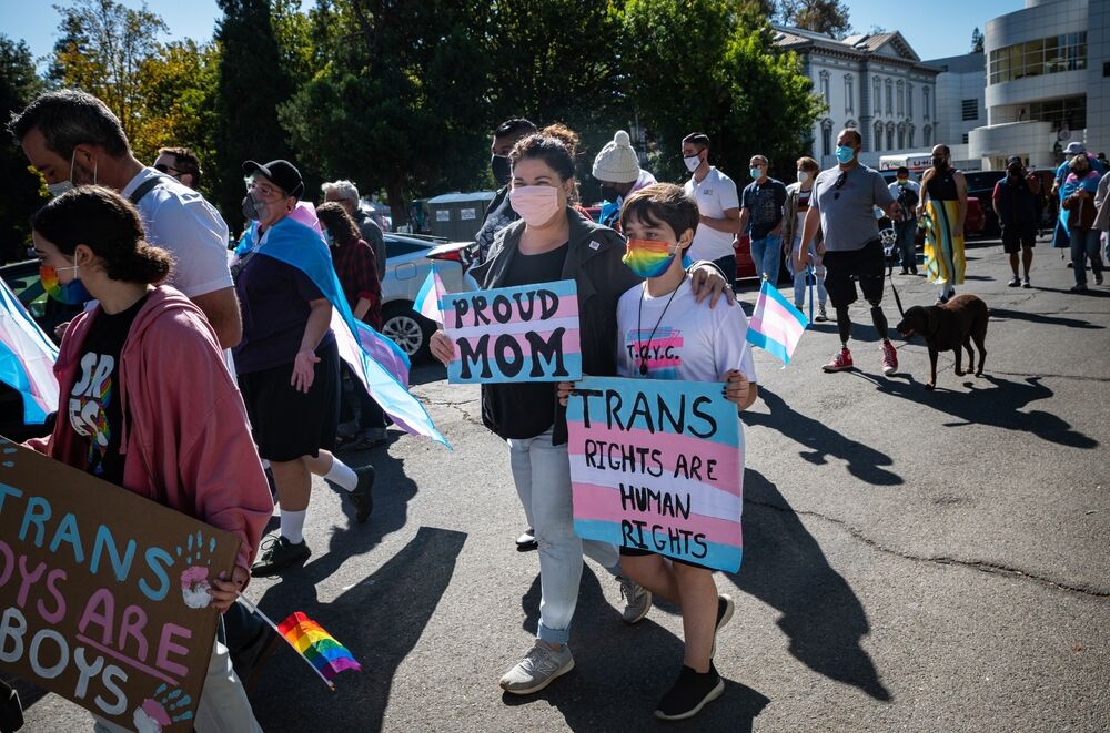SACRAMENTO, CA, U.S.A. - OCTOBER 9, 2021: Two members of the Shadden family, mother and child, march with Proud Mom and Trans Rights are Human Rights signs during the National Trans Visibility March.