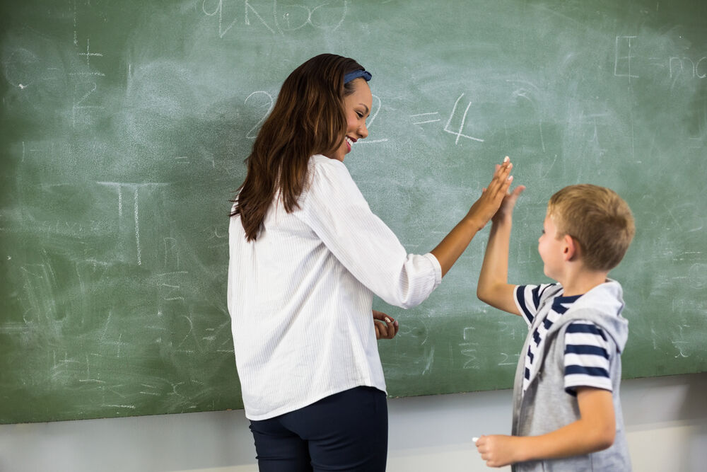 A teacher high-fiving a kid