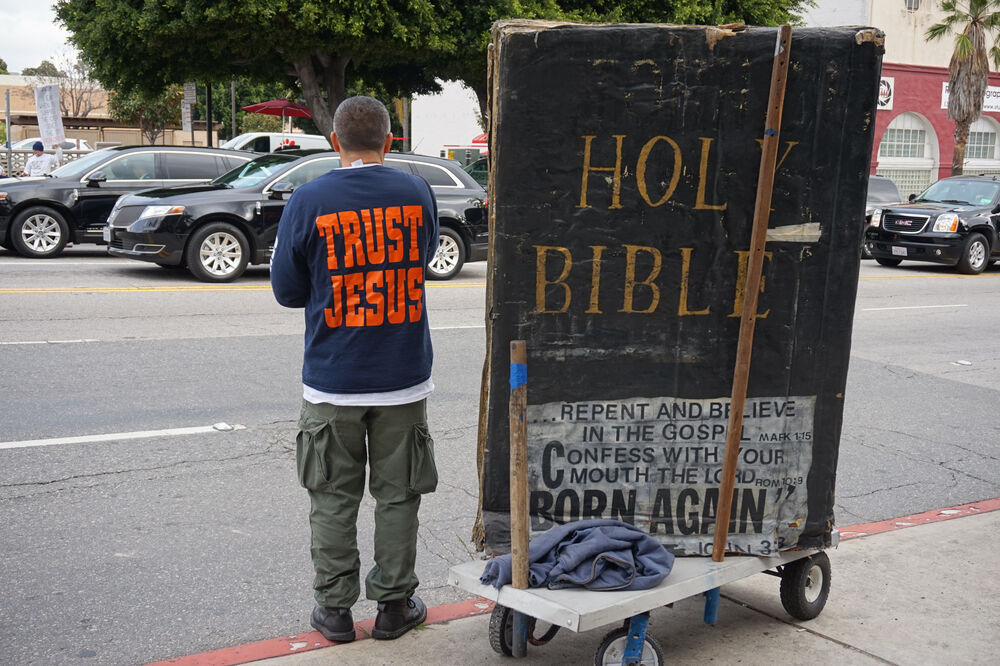 FEB 26TH, 2017: A religious protester in a "Trust Jesus" shirt stands next to a giant bible replica as limousines go by on their way to the red carpet area at the 89th Academy Awards.