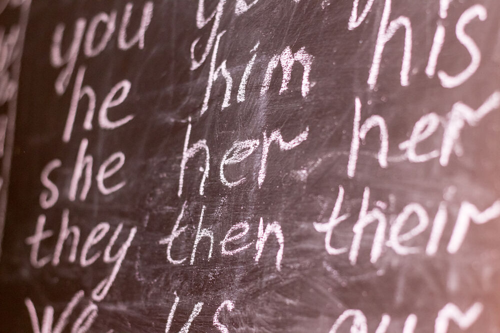 a chalkboard with he, him, she, her, they, them pronouns written on it