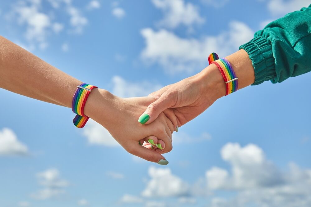 two people holding hands with painted nails and rainbow bracelets