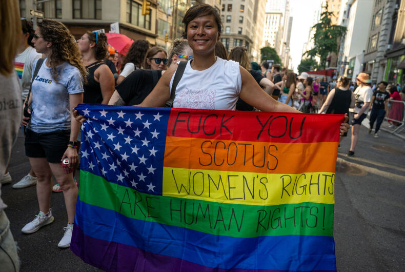 NEW YORK, NEW YORK - JUNE 25: A woman holds a "fuck you SCOTUS, women's rights are human rights" painted over a pride-colored American flag while participating in the 30th Annual New York City Dyke March on June 25, 2022 in New York City. The Dyke March which calls itself a march protest, rather than a parade, is a "demonstration of our First Amendment right to protest" according to their website. This year’s theme is Dykes for Trans Liberation.