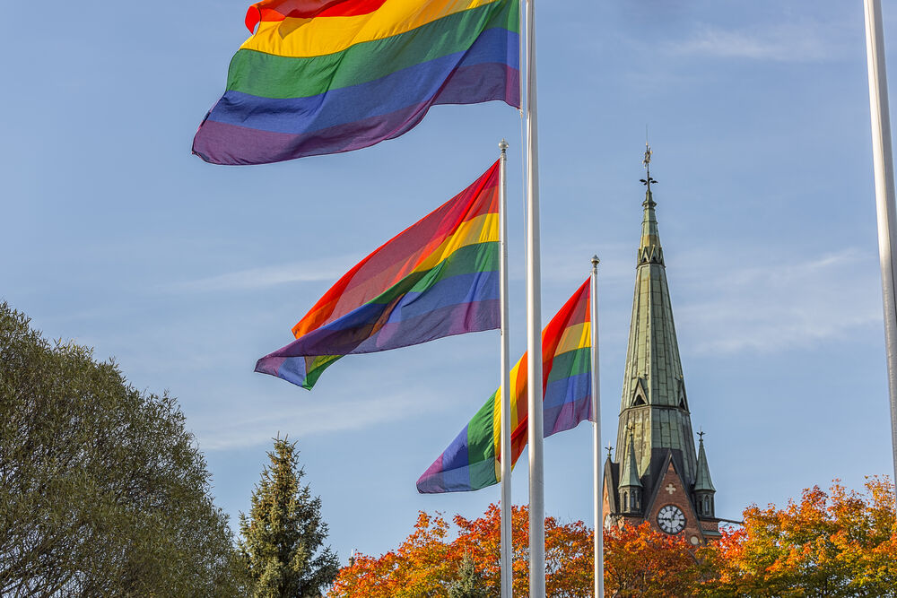 Church steeple with rainbow flags nearby