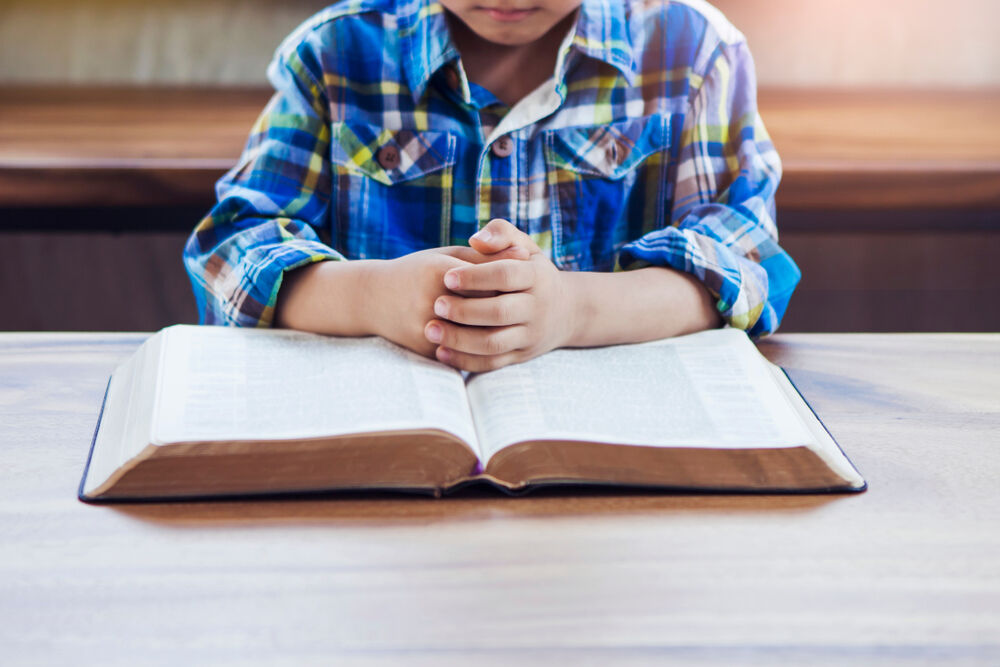 A child praying in front of a book