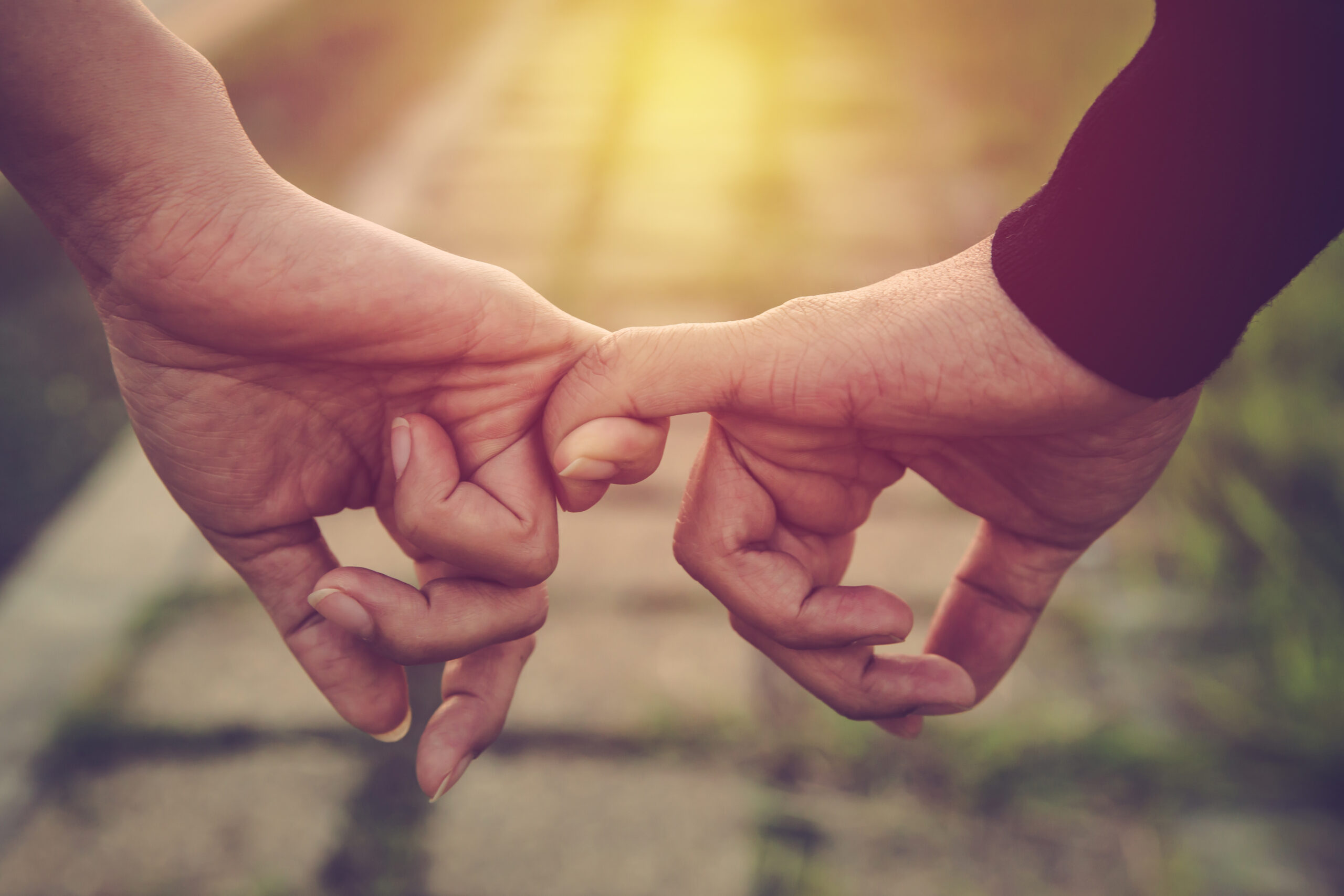 Hands intertwined by one finger from each person