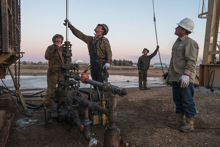 Oil field workers with Wisco work on a pump jack in Tioga, North Dakota. Photo by Getty Images