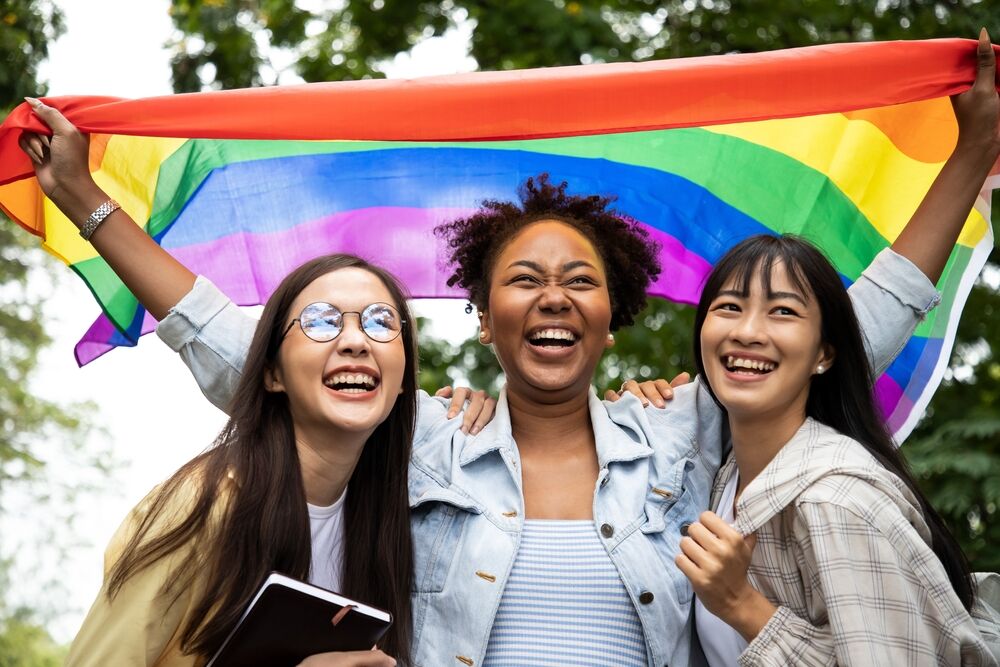 Three people with a rainbow flag, a stock image