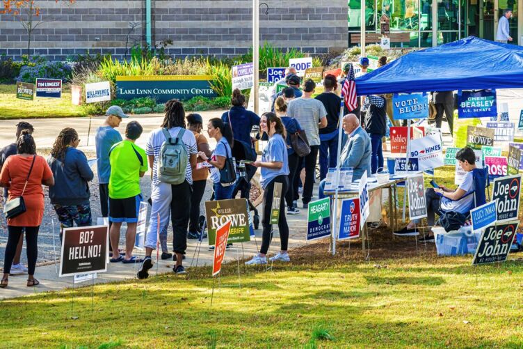 Volunteers hand out information about candidates while people stand in line to vote in Raleigh, North Carolina, on November 5, 2022.