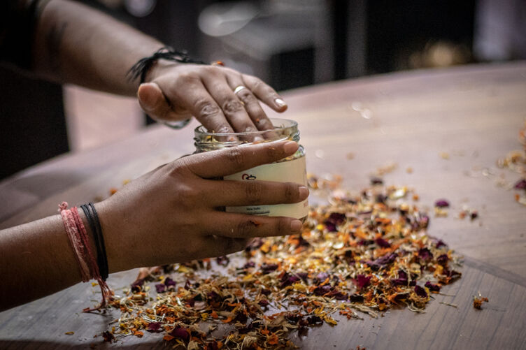 A resident puts discarded flowers inside a glass jar to make potpourri at Garima Greh