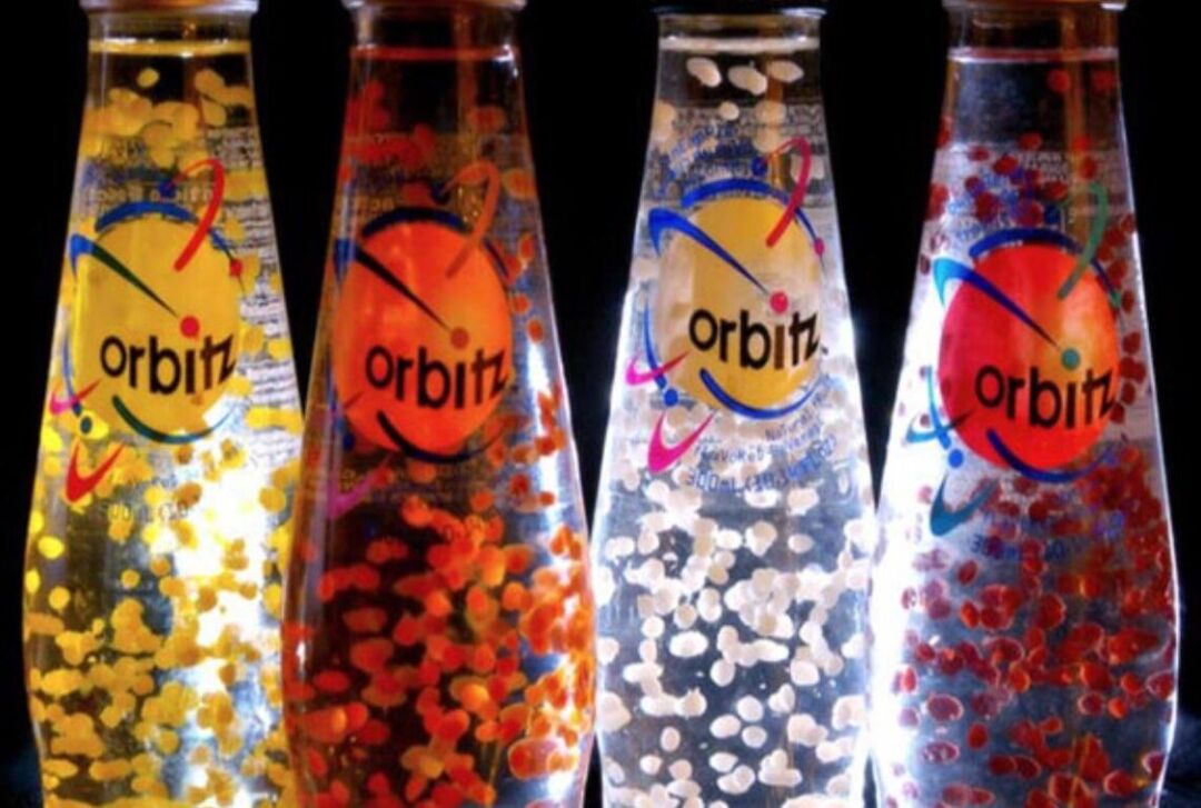 Close-up of the 90s drink, Orbitz, with a bright light behind the clear glass bottles to highlight the orbs inside