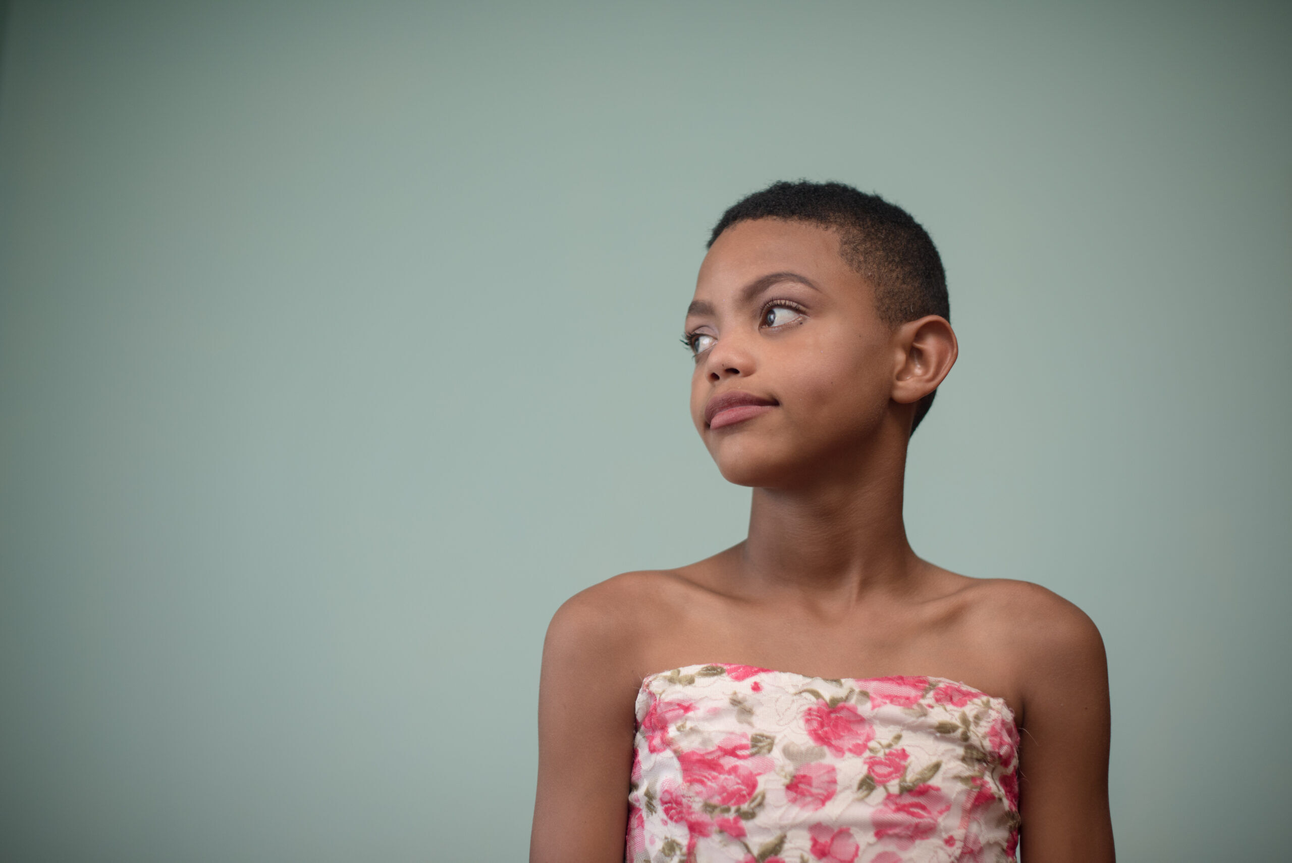 Young boy wearing a white and pink flowered dress