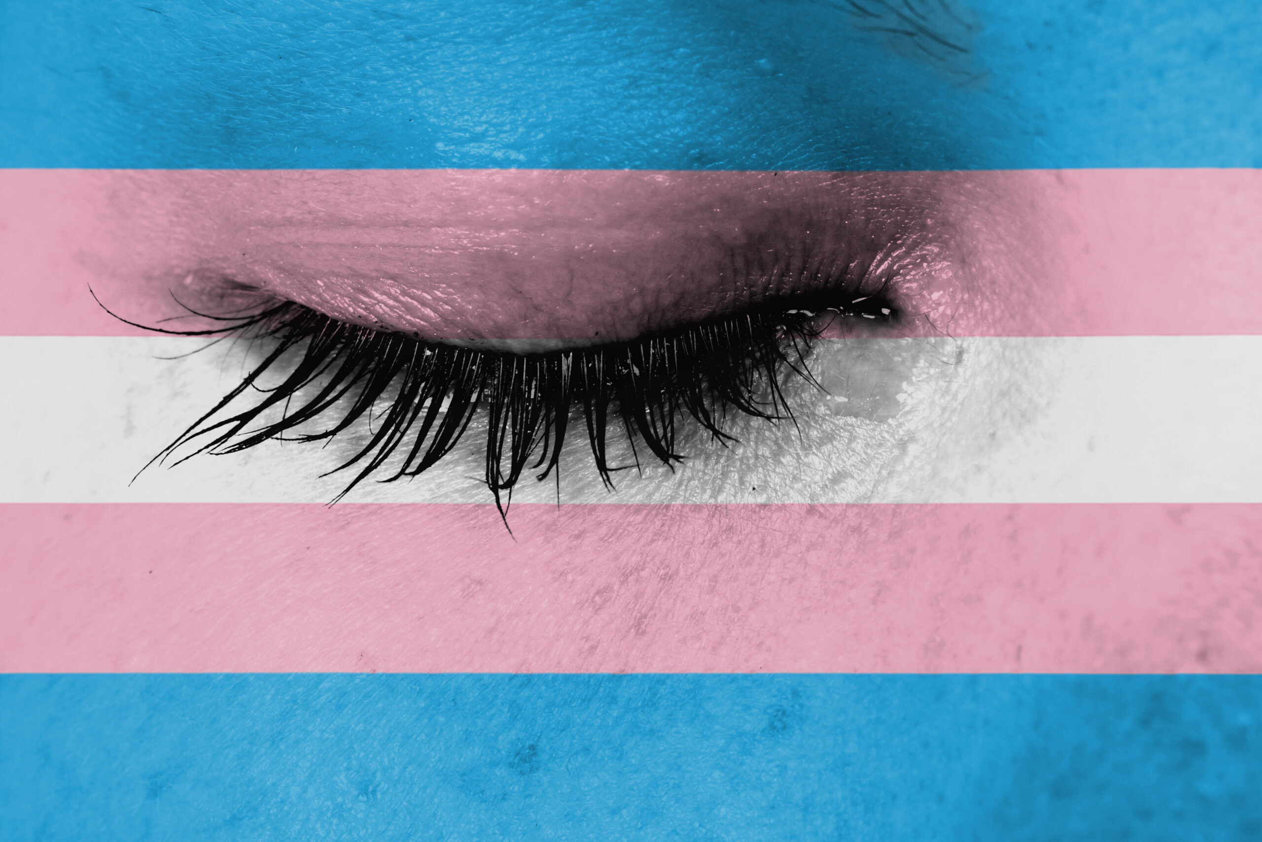 Close up of a closed eye against a trans flag