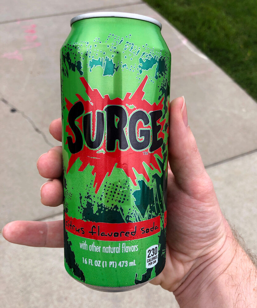 A can of the famed 90s citrus flavored soda, Surge, in a person's hand