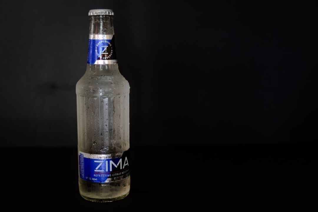 a bottle of Zima, the clearmalt 90s drink, on a black backdrop