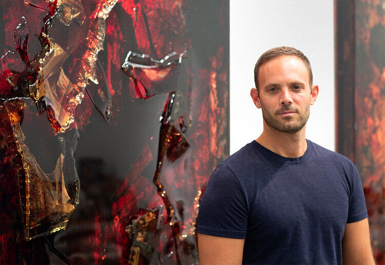 Artist and activist Jordan Eagles beside one of his artworks made with blood