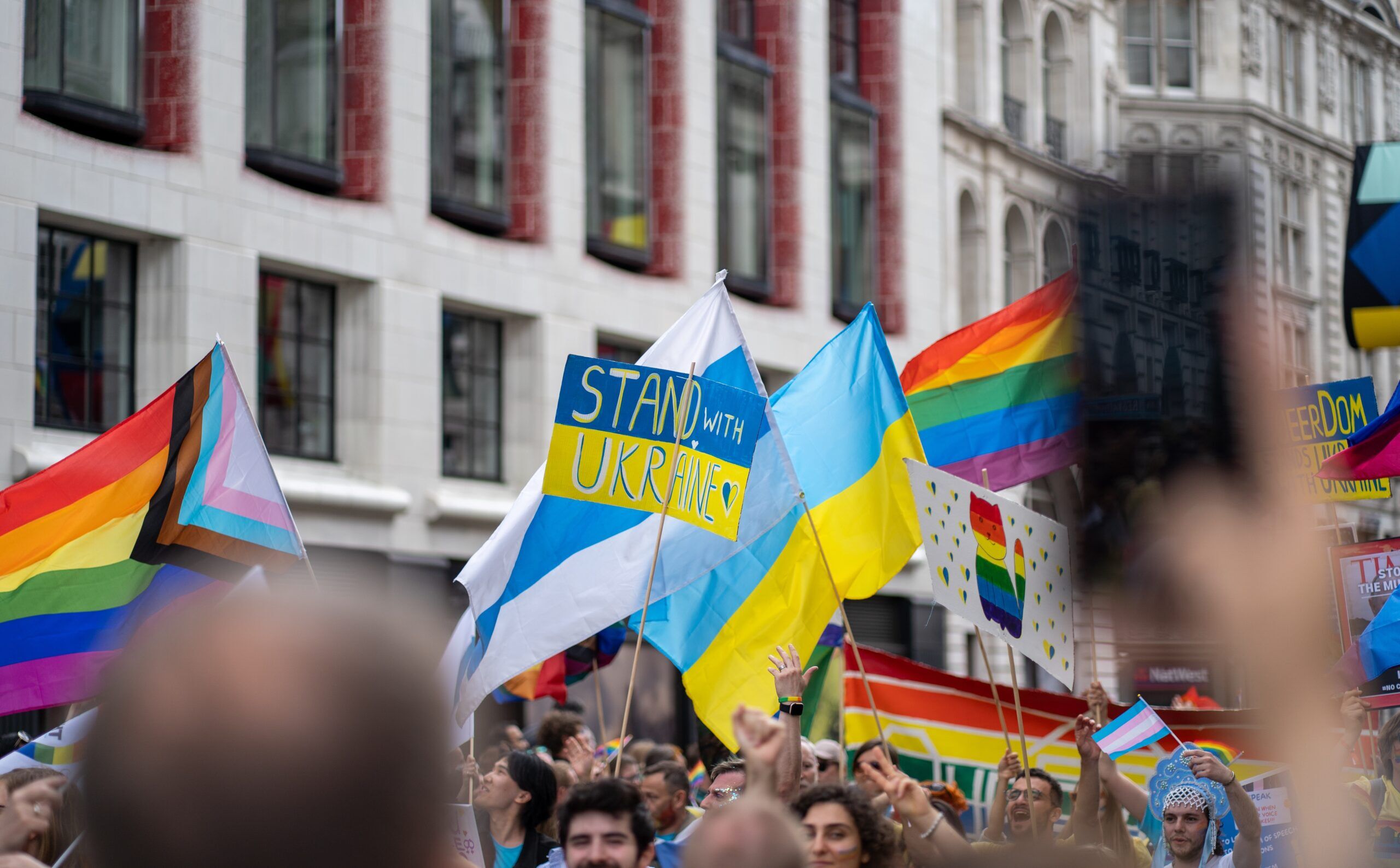 London, UK - 2 July 2022: person standing with a Ukraine protest sign amongst LGBTQ+ Pride flags