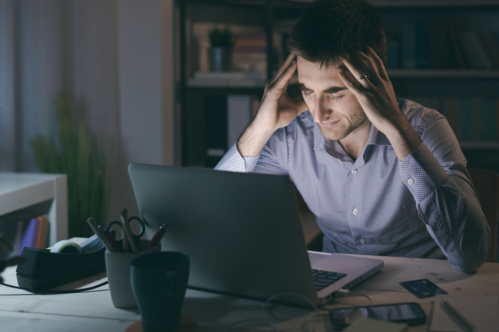 A man looking at a computer at night, and he's not well. maybe he's a closeted Utahan, but really it's just a stock image