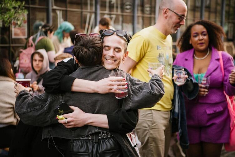Community members hug as they celebrate the launch of Polyambrewous. 