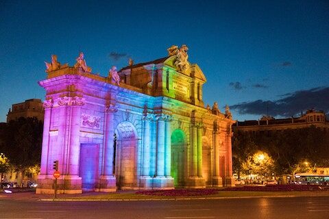 a building in madrid lit up in colorful rainbow lights for Madrid Pride