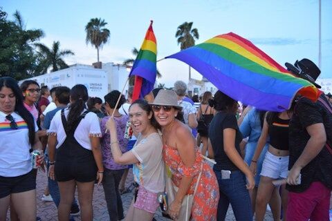 two women celebrating Playa Pride holding rainbow flags