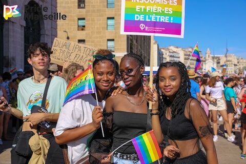 a group pose for the camera at Pride Marseille holding rainbow flags and signs