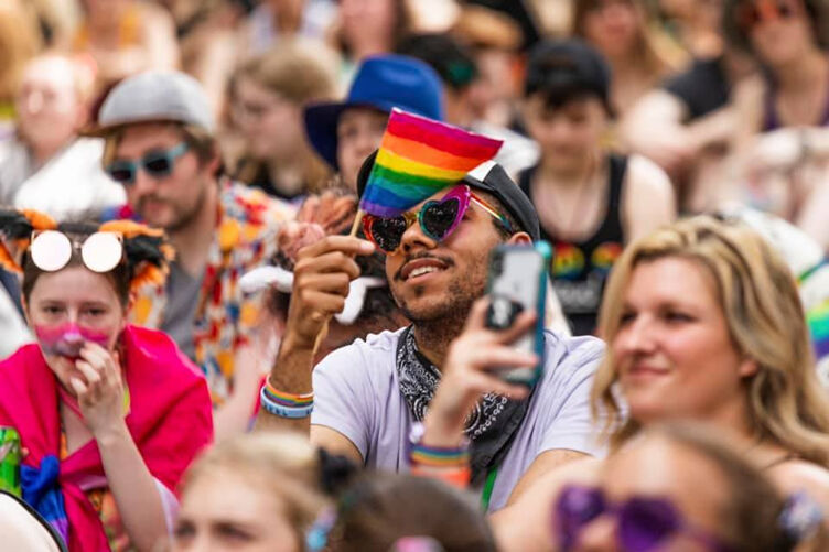 a person wearing heart-shaped rainbow sun glasses holds a pride flag at Twin Cities Pride