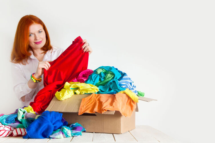 Woman going through box of rainbow colored clothes