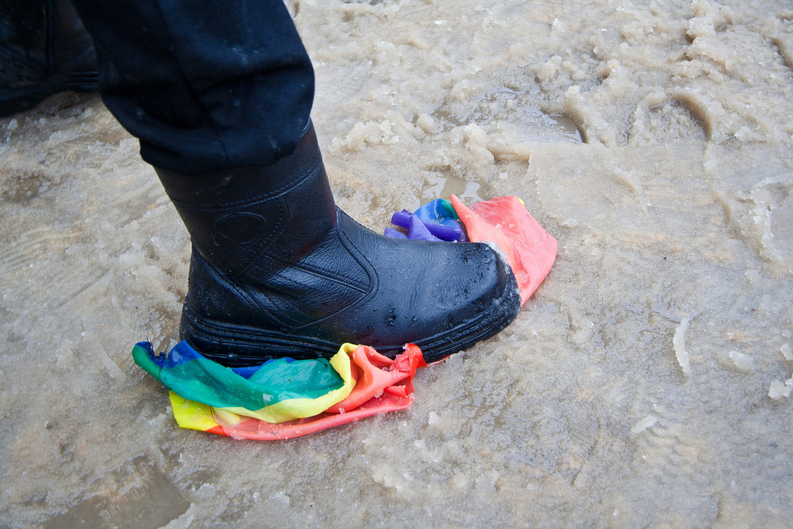 Foot stomping on a Pride flag in the sand