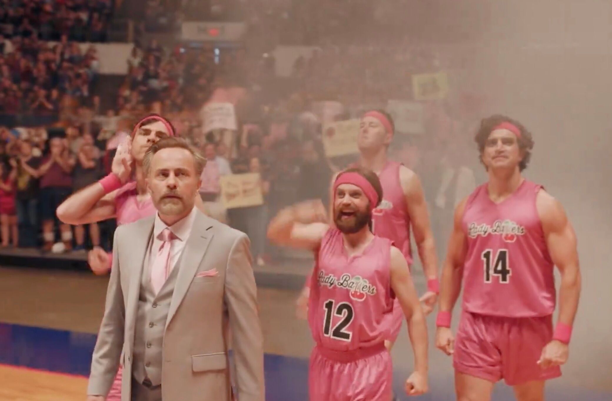 Scene from Lady Ballers: Group of cis men in pink jerseys pretending to be trans women walk out onto a basketball court
